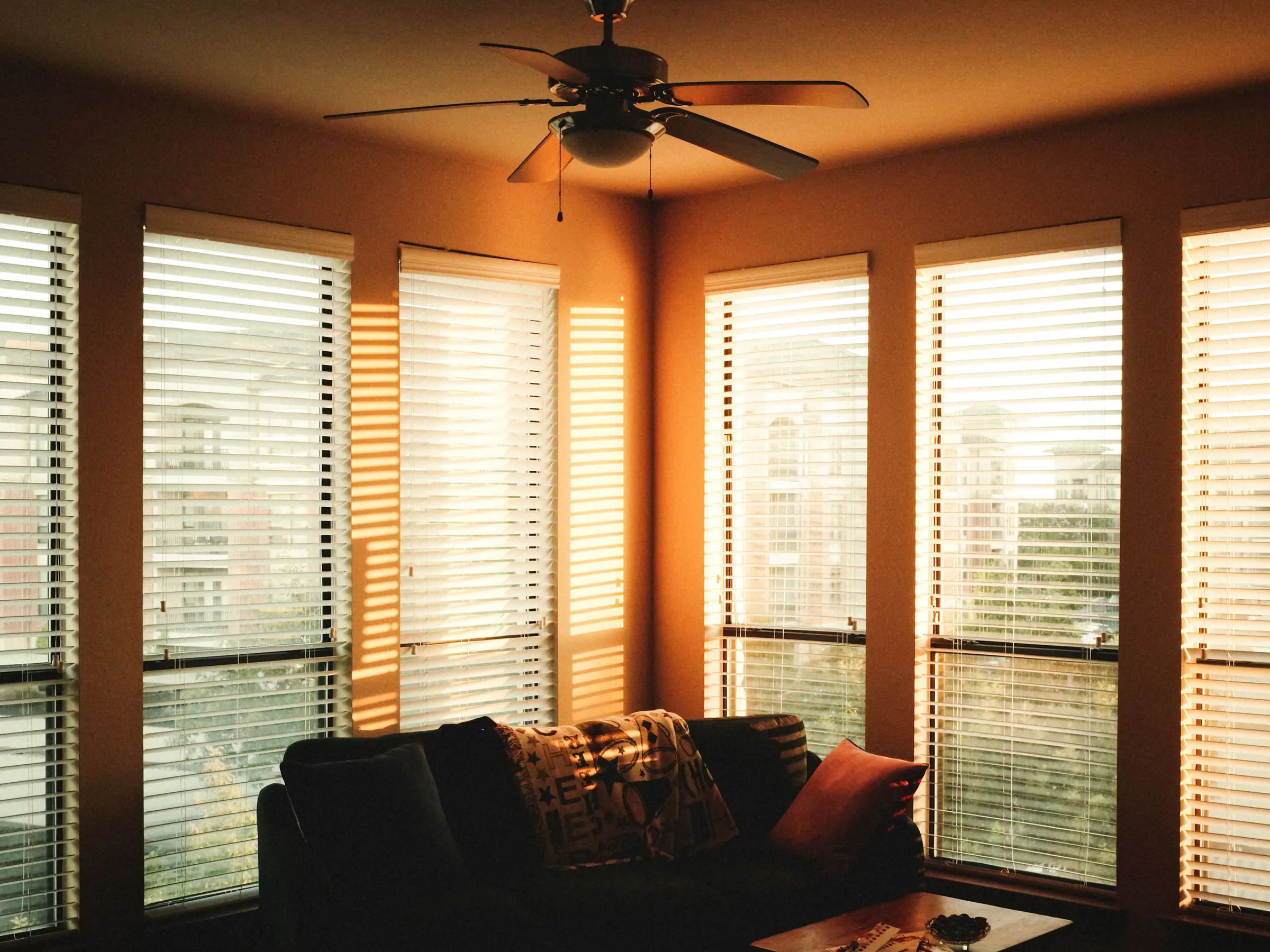 A living room with window blinds glowing in the evening light