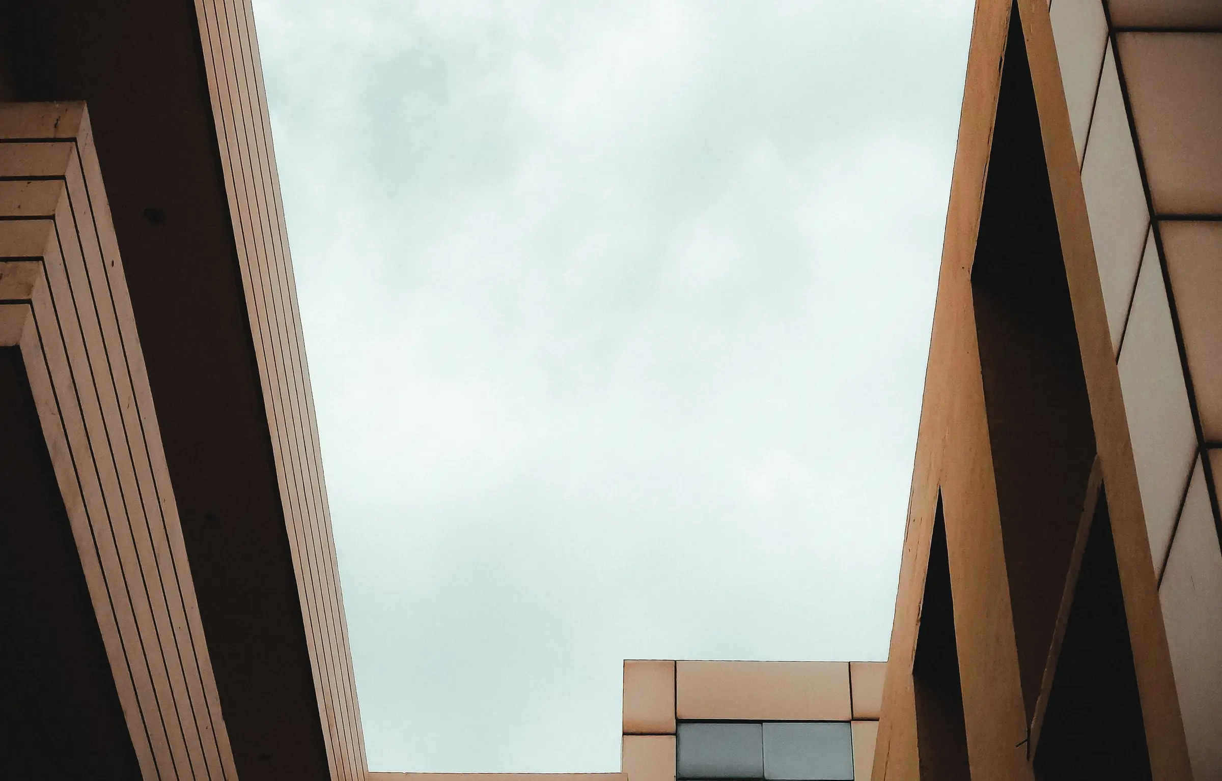 Looking up at a building facade with strong geometric lines against a pale sky