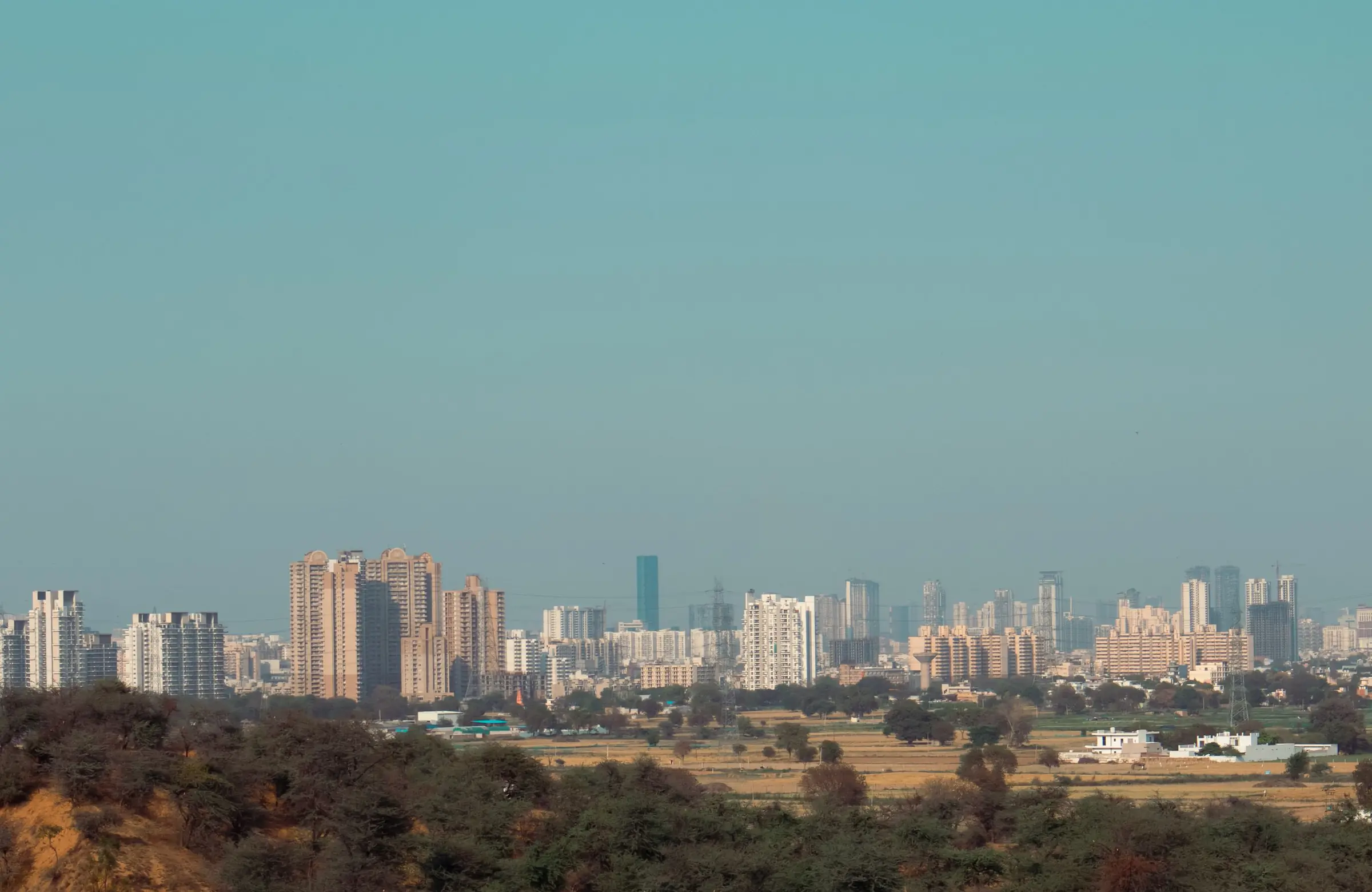 The Gurugram skyline in the distance, seen across scrubland under a clear sky